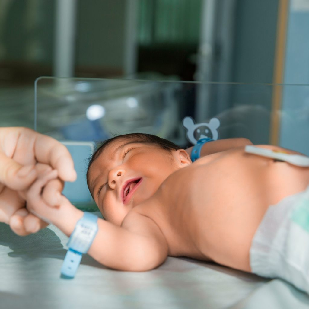 father holds hand of newly born babe in diapers